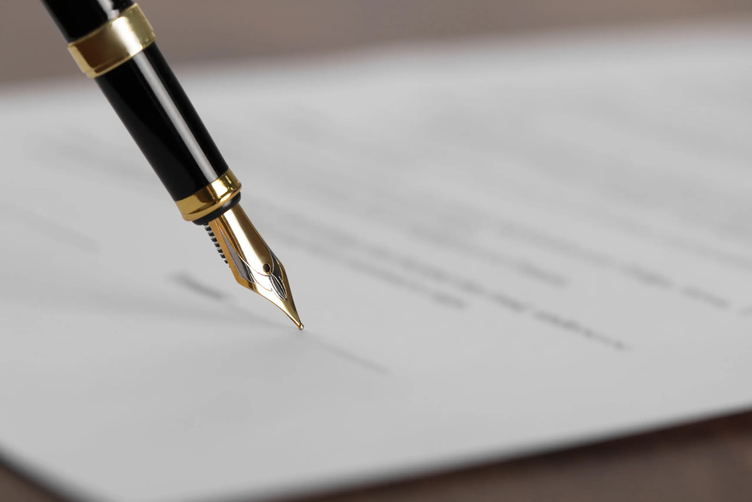 Writing on document with fountain pen at wooden table, closeup a